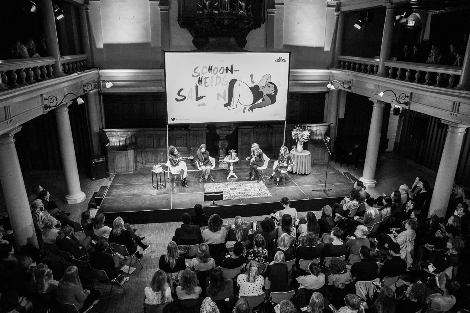 Publiek en sprekers tijdens De Schoonheidssalon in de zaal van de Rode Hoed